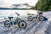 Ubco 2x2 off-road electric adventure bikes available at Rhino Adventure Gear shown riding through sand on beach