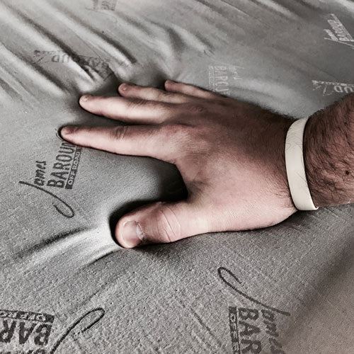 A hand sinking into the 3" foam mattress that comes with all James Baroud Roof Top Tents