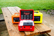 Three types of trauma kits for off road travelers, shown with red outback first aid kit opened on picnic table