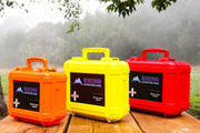 Three sizes of wilderness first aid kits designed to be carried in off road vehicles displayed on picnic table