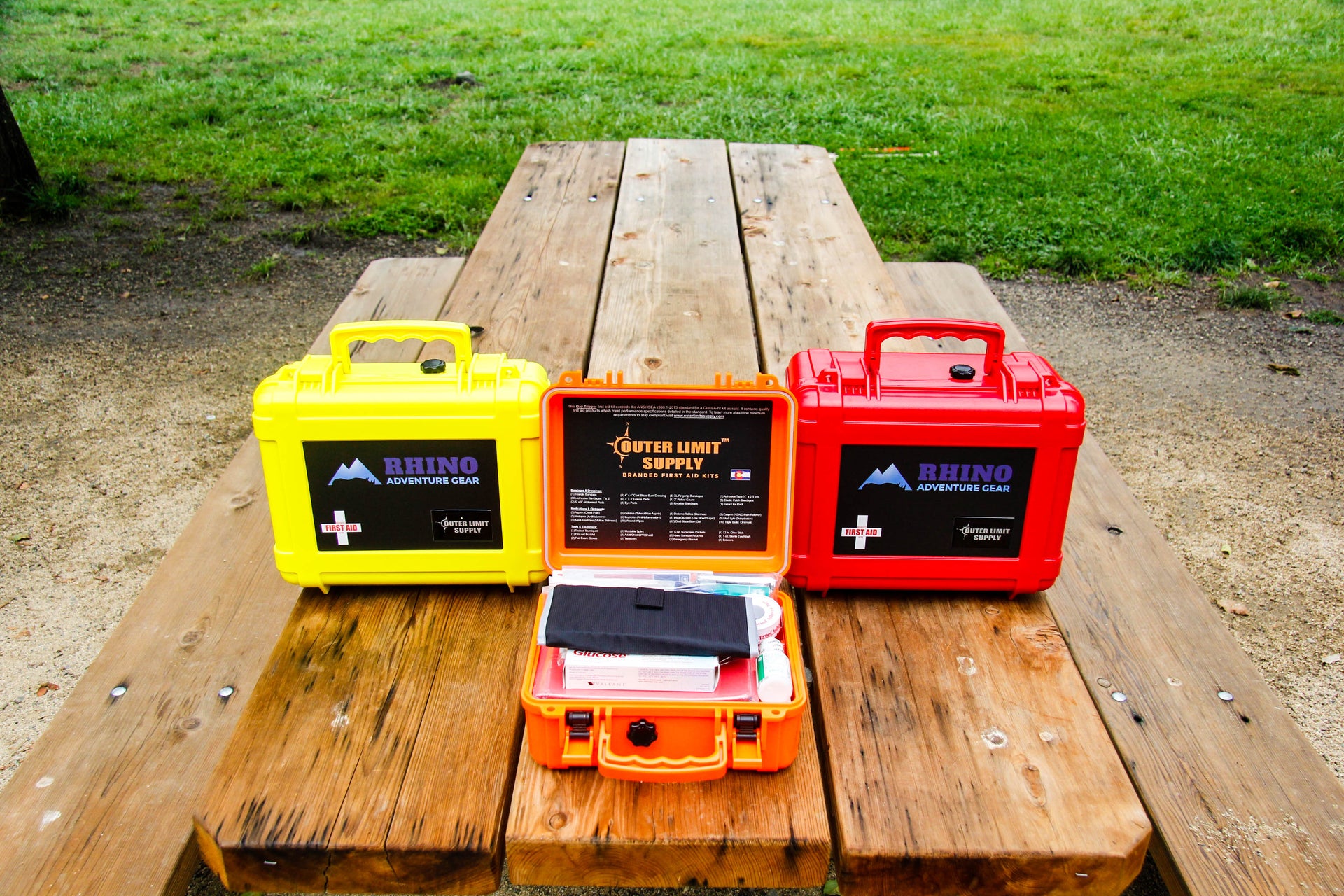Three sizes of wilderness first aid kits designed to be carried in off road vehicles displayed on picnic table