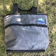 grey Adventure Tote Bag shown laying on its side with black nylon handles