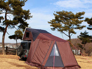 Annex room ground enclosure extension for iKamper Skycamp roof top tent. The annex room is shown zipped onto the door of the iKamper roof top tent and extends at ground level adjacent to the vehicle