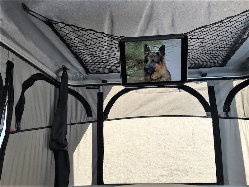 Tablet holder clipped to ceiling net in roof top tent