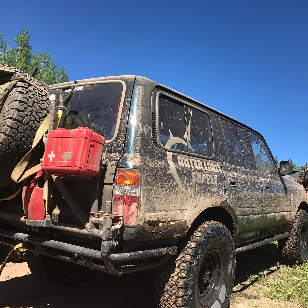 Overland vehicle with dust proof crush proof heavy duty first aid kit mounted on back of vehicle next to spare tire and trasharoo
