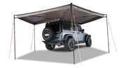 Right Side Mounted Rhino Rack Batwing Awning shown set up with 4 legs extended and tie downs staked in ground