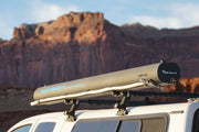Road Shower 4L solar heated camping shower mounted on vehicle roof rack with scenic red rock landscape in background