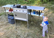 Toddler standing next to family camp kitchen from Trail Kitchens