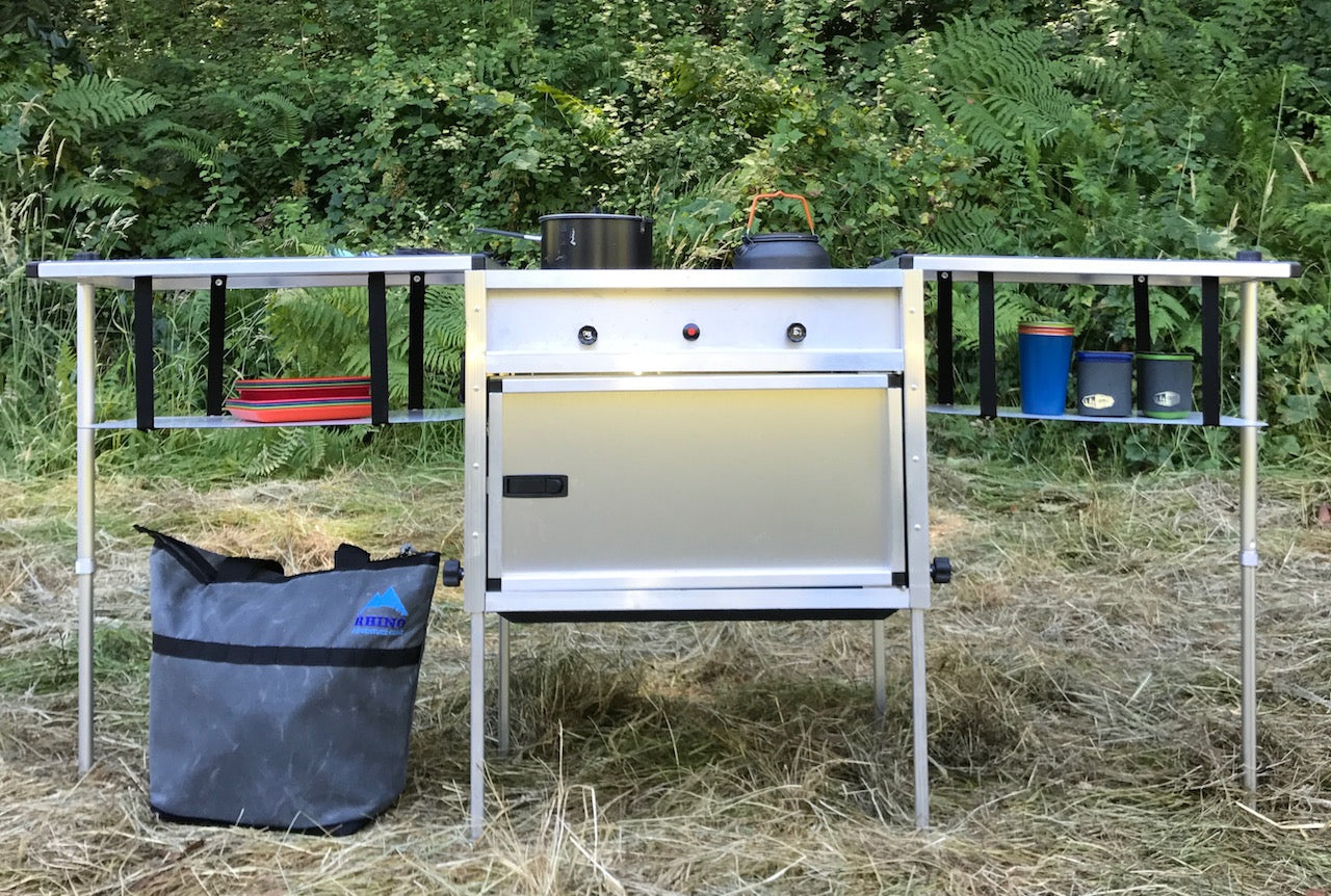 Trail Kitchens Camp Kitchen with Integrated Stove set up outdoors viewed head-on showing stove knob controls and shelving hanging below counters for additional storage