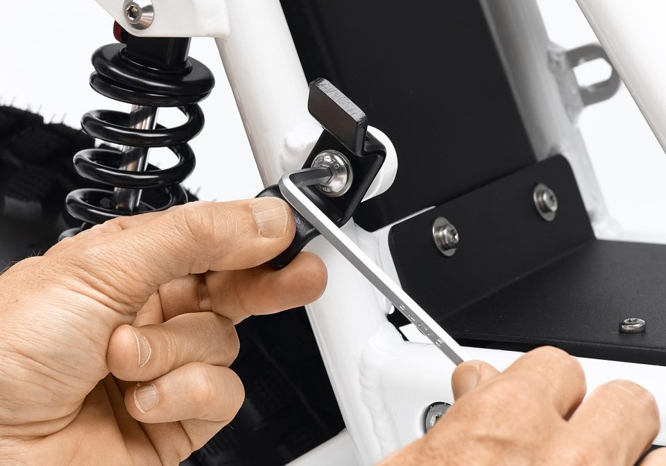 Detail of hands installing a tube adapter bracket from the 2x2 Adapter Pack to a lug on the Ubco 2x2 Electric Adventure Bike frame.