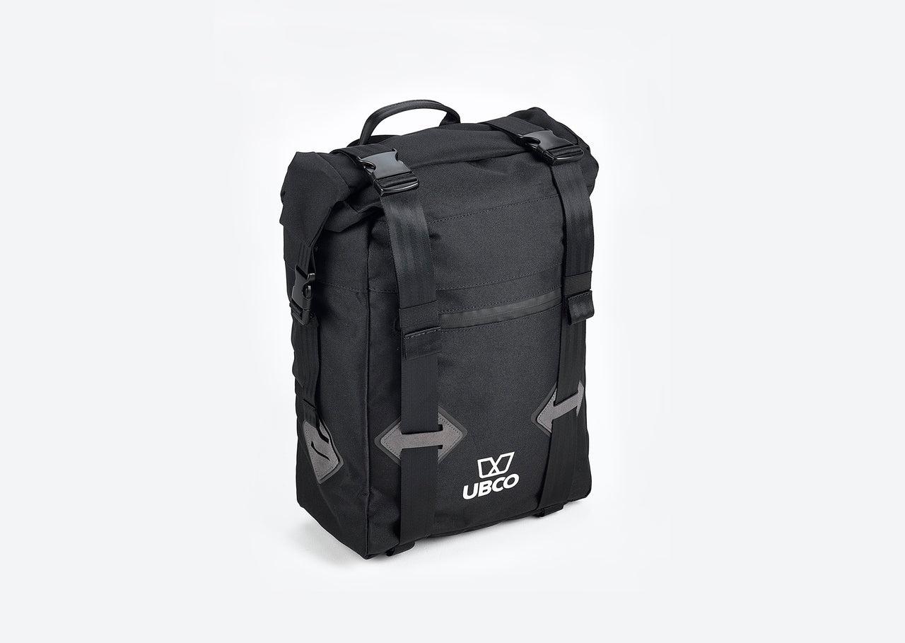 Diagonal view of Ubco 2x2 Pannier Bag. Pannier bag is thick black polyester with a handle on top and two wide vertical straps that buckle on the top and there is a small white Ubco logo branding near the bottom of the bag.