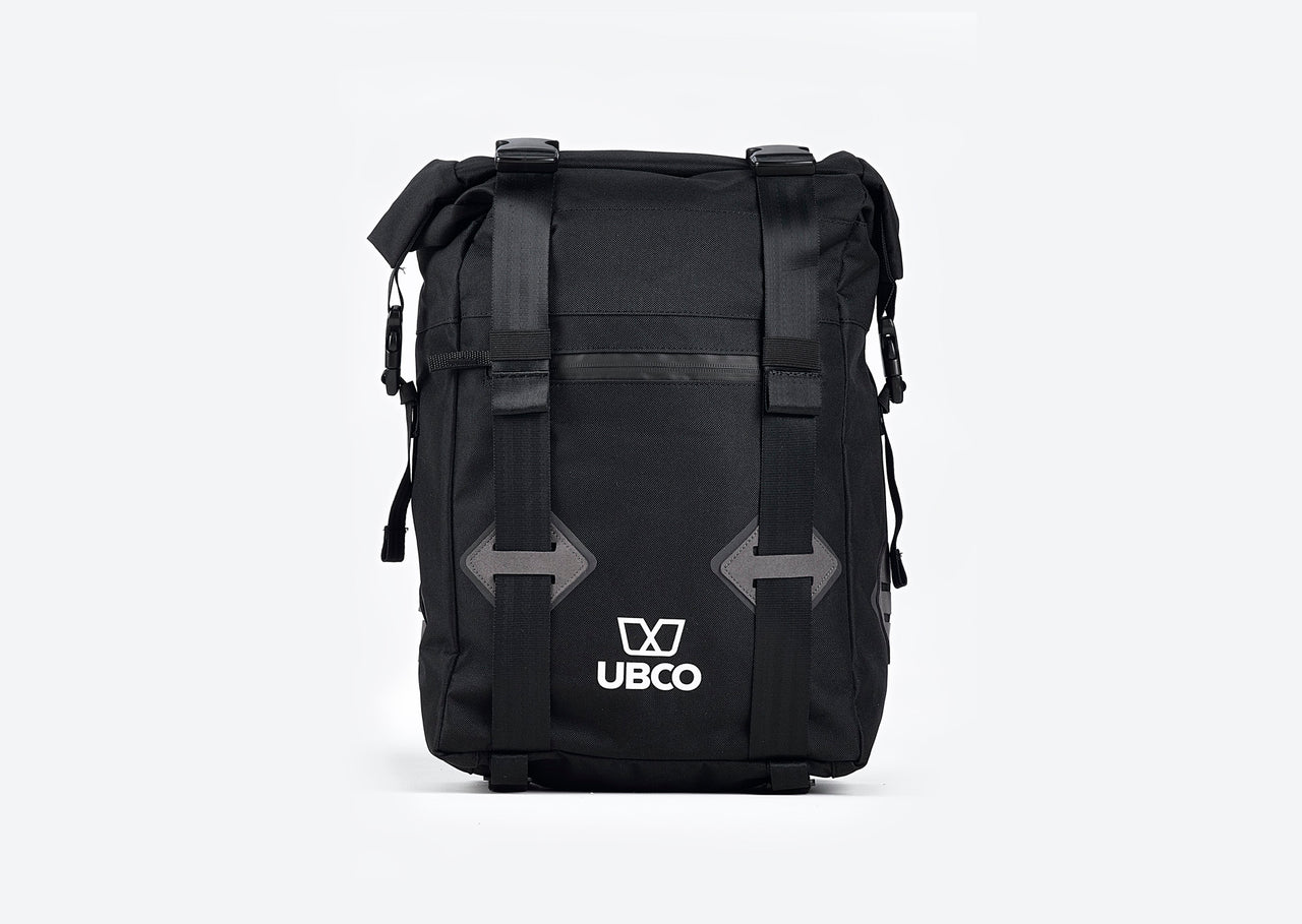 Front view of Ubco 2x2 Pannier Bag. Pannier bag is thick black polyester with a handle on top and two wide vertical straps that buckle on the top and there is a small white Ubco logo branding near the bottom of the bag.