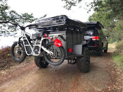 ubco 2x2 2017 off road electric adventure bike from Rhino Adventure Gear shown mounted on bike rack behind off road trailer during overlanding trip