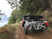 Ubco 2x2 electric dirt bike mounted on carrying rack towball mount of off road overland trailer in scenic northern california